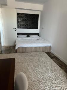 a white bedroom with a bed and a rug at Apartament bloc nou - self check in - free parking in Craiova