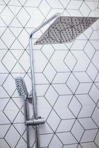 a shower head in a bathroom with white tiles at Luxury 2-Bedroom Apt at Achimota in Taifa