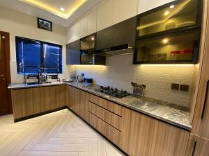 a large kitchen with wooden cabinets and a window at Firefly Retreat-your home away from home in Rawalpindi