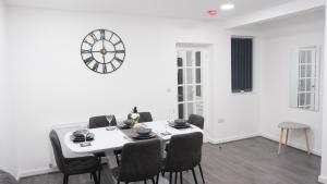 a dining room with a table and a clock on the wall at EtihCity - 3 Bedroom Semi with Sky n Netflix near Etihad Football Stadium, Tourist attractions, Manchester City Centre Transport Links and Opposite to McDonald's in Manchester