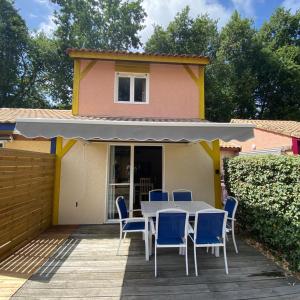 einen Tisch und Stühle auf einer Terrasse mit einem Haus in der Unterkunft Villa Soustons Plage / Résidence les villas du lac avec piscine in Soustons