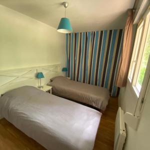 ein kleines Schlafzimmer mit 2 Betten und einem Fenster in der Unterkunft Villa Soustons Plage / Résidence les villas du lac avec piscine in Soustons