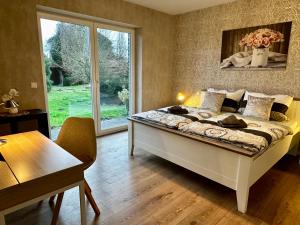 Schlafzimmer mit einem Bett, einem Tisch und einem Fenster in der Unterkunft Ferienhaus am Glück in Bad Zwischenahn