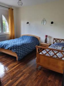een slaapkamer met 2 bedden en een houten vloer bij Maison proche de la mer in Pleslin-Trigavou