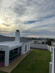 a white house with a roof with a yard at REst house in Langebaan