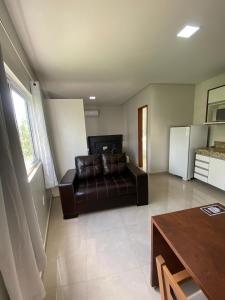 a living room with a leather couch and a table at Flats Grangeiro in Crato