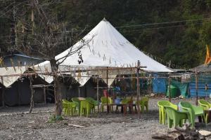 a tent with chairs and a table in front of it at Wild Leaf Camps in Rishīkesh