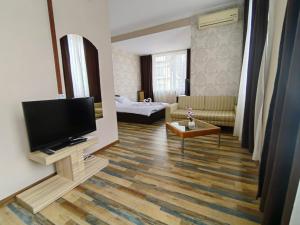 uma sala de estar com uma televisão e um sofá em Хотел Приятели em Vratsa