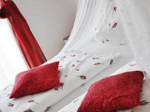 a white bed with red pillows on it at Pension Kreuzberghof in Großklein +9 photos