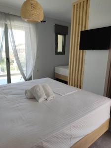 a bedroom with a white bed with two towels at Olivar del Mar in Nydri