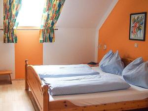a bed in a bedroom with an orange wall at Pension Kreuzberghof in Großklein