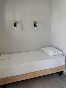 a bed with white sheets and two lights on the wall at Olivar del Mar in Nydri