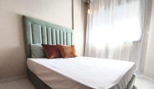 Schlafzimmer mit einem Bett mit blauem Kopfteil und einem Fenster in der Unterkunft Appart relax aéroport 5 min in Nouaceur