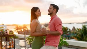 um homem e uma mulher de pé numa varanda com uma bebida em The Villas Cancun by Grand Park Royal - All Inclusive em Cancún