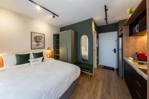a bedroom with a large white bed and green walls at Charlie Panorama Butantã in Sao Paulo