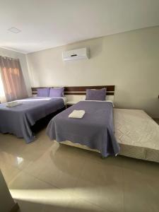 a bedroom with two beds with purple sheets at Flats Grangeiro in Crato