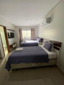 a hotel room with two beds and a television at Flats Grangeiro in Crato