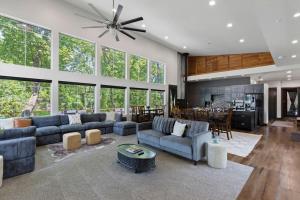 a living room with blue couches and a kitchen at LUX Treehouse on Private Lake next to Lake Conroe with Game room, Paddleboards, Lake Views, and more! in Montgomery