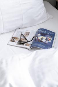 an open book on a bed with white sheets at Beach Trail apartments by Daniel&Jacob's in Copenhagen