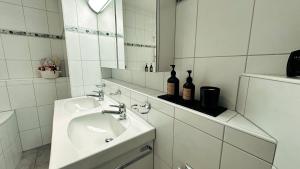 W białej łazience znajduje się umywalka i lustro. w obiekcie Piz Alpina die grosse, moderne Wohnung mit Bergsicht w Davos