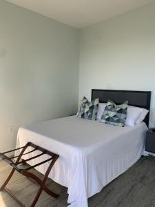 um quarto com uma cama grande com lençóis brancos e almofadas em Nonsuch Falls - Journey to Paradise - Modern Waterfall Escape em Breastworks