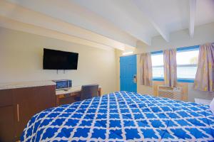 1 dormitorio con 1 cama, escritorio y TV en Aladdin Motel By OYO Merritt Island en Merritt Island
