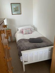 a small bedroom with a white bed with a pillow at Five Farthings Stylish cottage in Littleworth