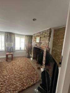 a living room with a stone fireplace and a television at Five Farthings Stylish cottage in Littleworth