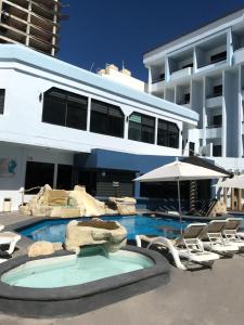 a large building with a swimming pool with chairs and an umbrella at Olas Altas Inn Hotel & Spa in Mazatl&aacute;n