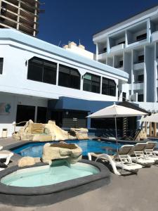 a large building with a swimming pool with chairs and an umbrella at Olas Altas Inn Hotel & Spa in Mazatlán