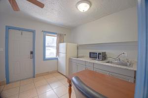 a kitchen with a table and a sink and a refrigerator at Aladdin Motel By OYO Merritt Island in Merritt Island