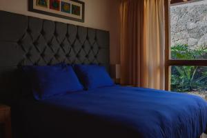 1 dormitorio con cama azul y ventana en La Hacienda Tepoztlán Awarded - Firenze Entremuros, en Tepoztlán