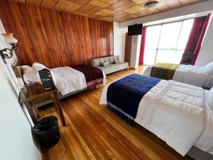 a bedroom with two beds and a couch in it at Hotel El Morlaco in Cuenca