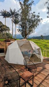 a tent and two chairs on a patio with a table at Glamping Reserva del Roble in La Vega