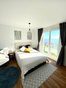 a bedroom with a large bed and a large window at Apartamentos LAMAROSA -LAS PLAYAS in Burela de Cabo