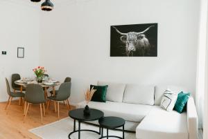 ein Wohnzimmer mit einer weißen Couch und einer Kuh an der Wand in der Unterkunft Ferienwohnung Elbzauber für 6 l Parkplatz l Balkon in Pirna
