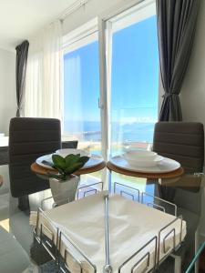 sala de estar con mesa, sillas y ventana grande en Apartamentos LAMAROSA -LAS PLAYAS, en Burela de Cabo