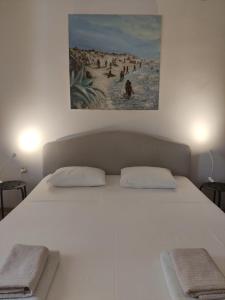 a white bed with two pillows and a painting above it at Spacious garden house, Orebić (4+1) in Orebić