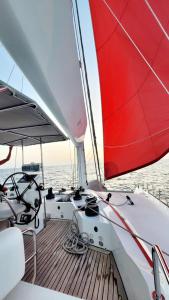 a boat with a red sail on the water at "Marea" Sunreef 62 Catamaran with Crew all inclusive in Isla Wichitupo Grande