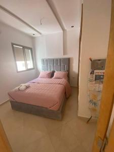 Panoramique appartement في القنيطرة: غرفة نوم مع سرير وملاءات وردية ونافذة