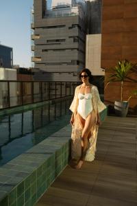 una donna con un vestito in piedi accanto alla piscina di Qoya São Paulo Paulista, Curio Collection by Hilton a San Paolo