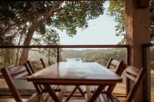 una mesa de madera y sillas en un porche con vistas al río en Fazenda sol nascente, en Pau dʼAlho