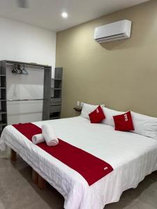 a bedroom with a large bed with red and white pillows at Hotel y Bungalows Bugambilias in San Patricio Melaque