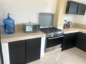 a kitchen with a stove and a microwave on a counter at Hotel y Bungalows Bugambilias in San Patricio Melaque