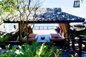 un patio con sombrilla y un sofá debajo. en Baan Hin Sai Resort & Spa, en Chaweng Noi Beach