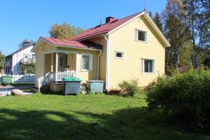 una casa amarilla con techo rojo en un patio en Hotel Aakenus Holiday Home Kymppi, en Rovaniemi