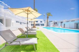 a row of lounge chairs and an umbrella next to a pool at Atlantic View 6B in Puerto del Carmen