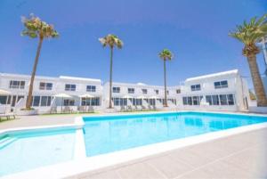a large swimming pool in front of a building with palm trees at Atlantic View 6B in Puerto del Carmen