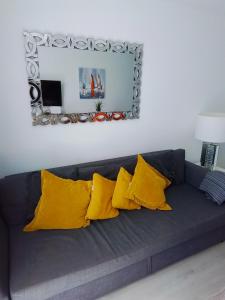 a black couch with yellow pillows and a mirror at Atlantic View 6B in Puerto del Carmen
