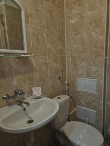 a bathroom with a sink and a toilet and a mirror at Хотел Приятели in Vratsa